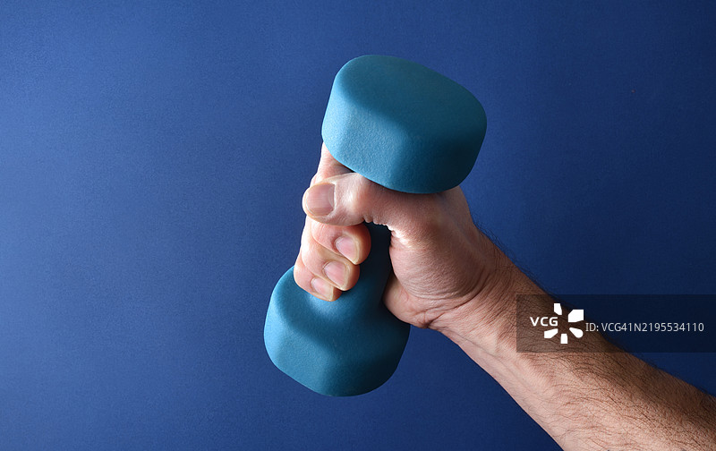 手握蓝色氯丁橡胶哑铃进行肌肉强化运动图片素材