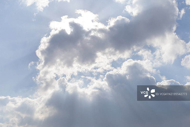 阳光透过蓝天的云层洒下。图片素材