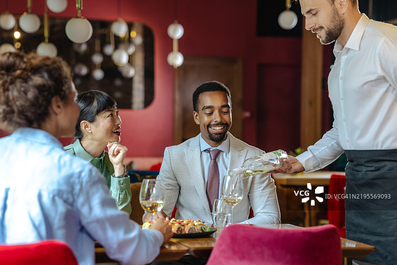 服务员在时尚餐厅为一群专业朋友提供服务图片素材