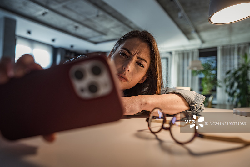 一位女性在桌前挣扎于疲惫，快要睡着了。图片素材