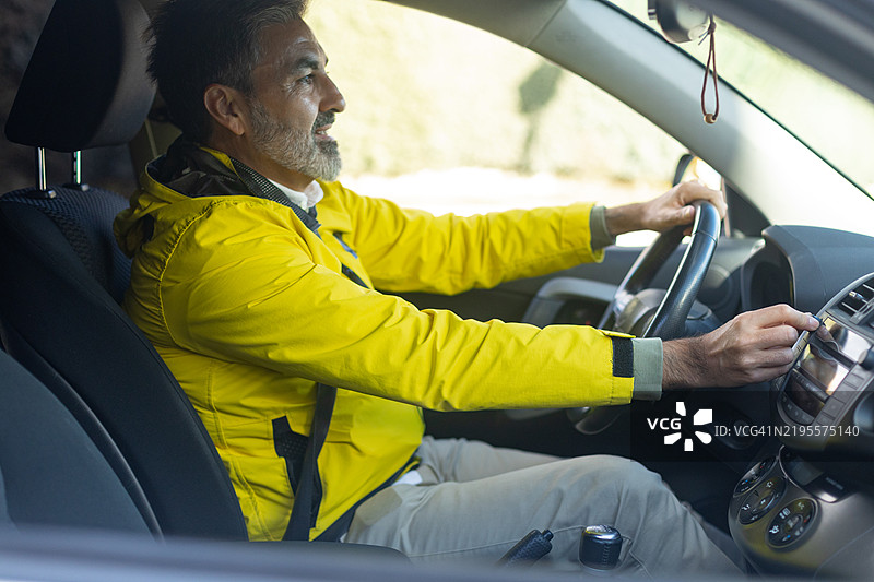 成熟男性驾驶汽车并打开汽车收音机图片素材
