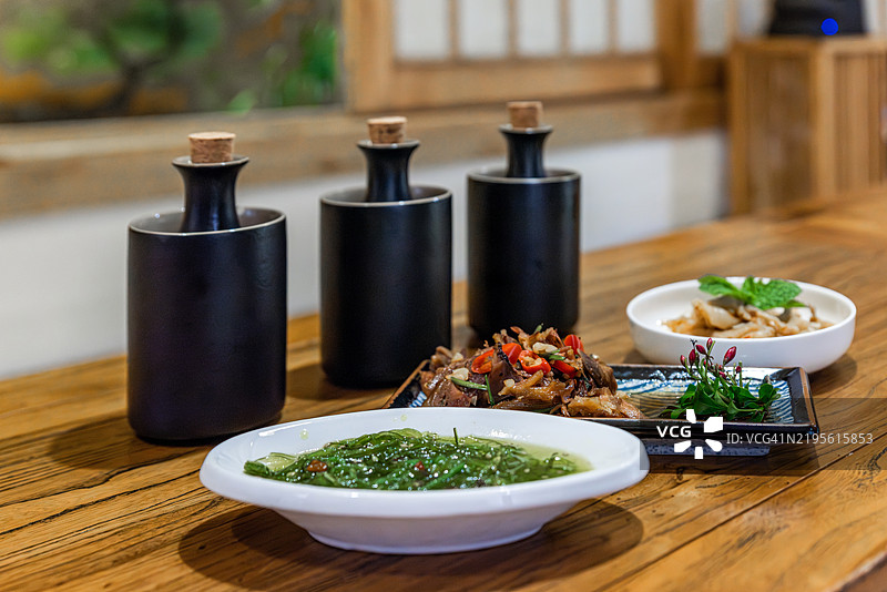 酒瓶、酒杯和盘子上的中式冷菜放在台面上图片素材