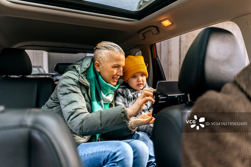 母亲和儿子在车后座上使用平板电脑图片素材
