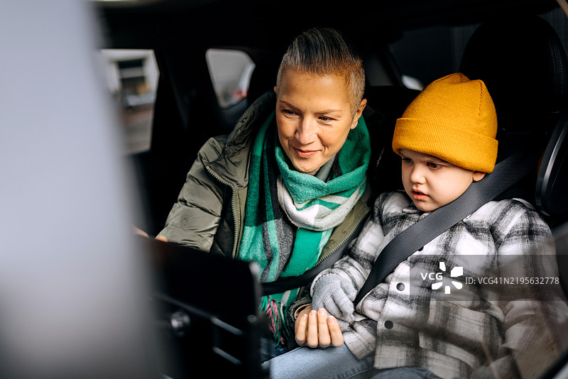 母亲和儿子在车后座上使用平板电脑图片素材