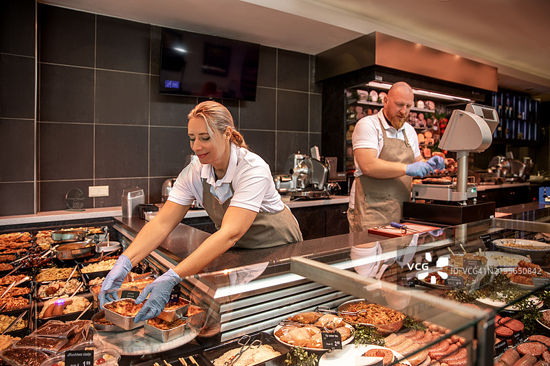 一名男性工人与一名女性肉贩在他们的店里一起工作图片素材