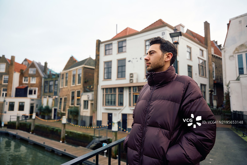 年轻男子在多德雷赫特市中心欣赏运河边的房屋图片素材