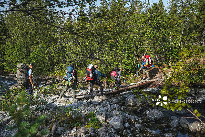 一群徒步旅行者在森林地形中穿越河流图片素材