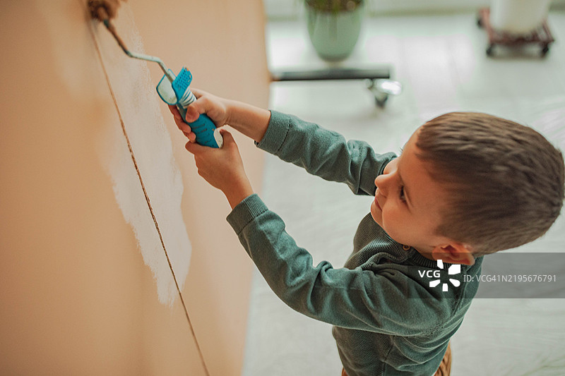 一个漂亮的孩子正在给墙壁画画图片素材