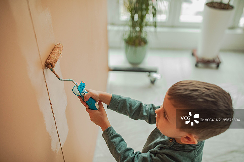 一个美丽的孩子正在给墙壁画画图片素材