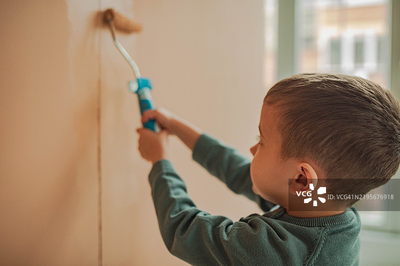 一个美丽的孩子正在给墙壁画画图片素材