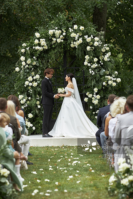 恋爱中的新娘们在美丽的花卉景观背景下手牵手。图片素材