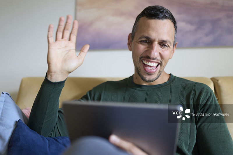 男人坐在沙发上使用平板电脑在家中图片素材