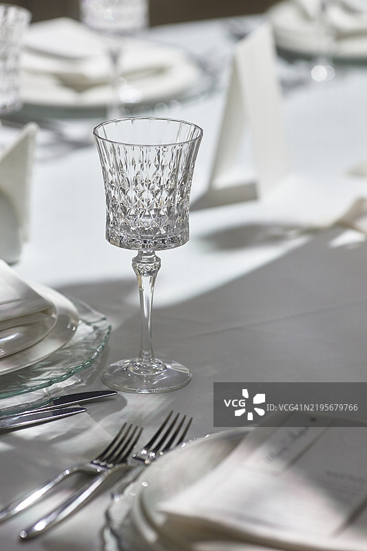 水晶酒杯装饰着阳光洒满的餐厅桌子。图片素材