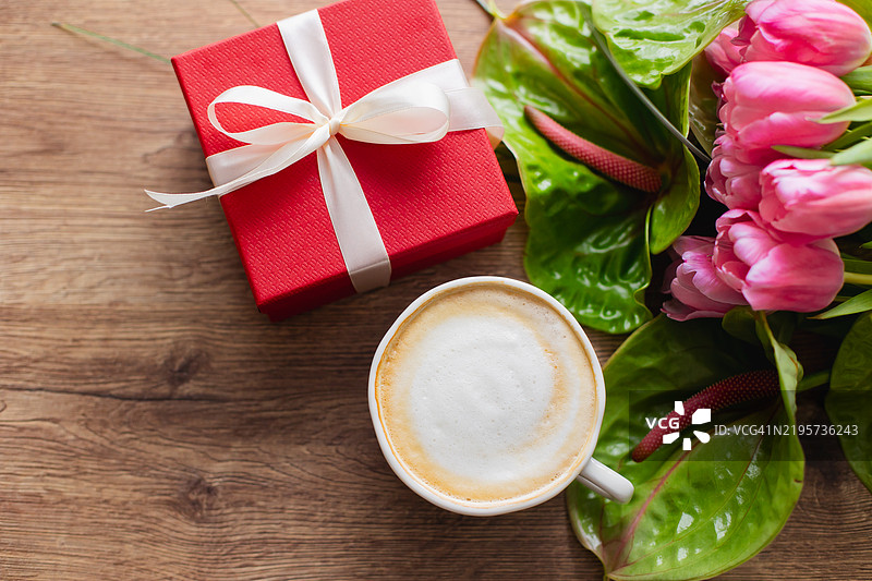春季花束，包含粉色郁金香和明亮的绿色卡拉，礼品盒和一杯咖啡。春天、复活节和母亲节的节日概念。图片素材
