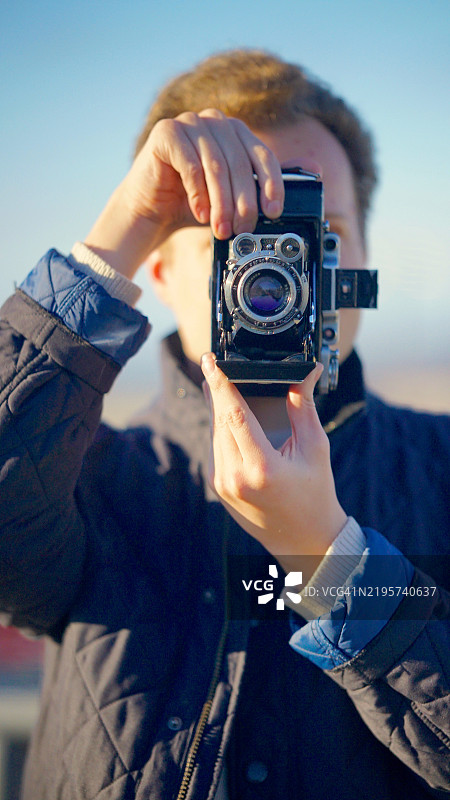 年轻男子使用复古相机的特写镜头图片素材