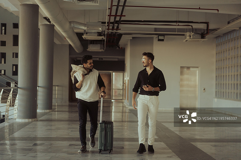 两位商人在机场航站楼内边走边谈图片素材