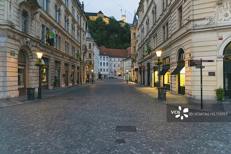 黄昏时分，空旷的鹅卵石街道，背景是欧洲建筑和位于山顶的卢布尔雅那城堡，斯洛文尼亚卢布尔雅那。图片素材