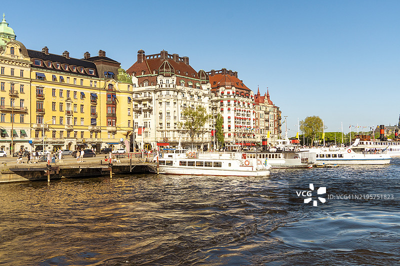 斯德哥尔摩海滨，优雅的建筑和游船在清澈的蓝天下，位于瑞典斯德哥尔摩的厄斯特马尔姆区。图片素材