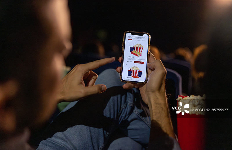 在电影院用手机应用点零食的男子图片素材