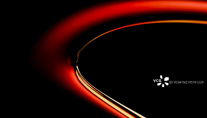 抽象的红色霓虹灯光曲线在黑色背景上形成平滑的弧形图片素材