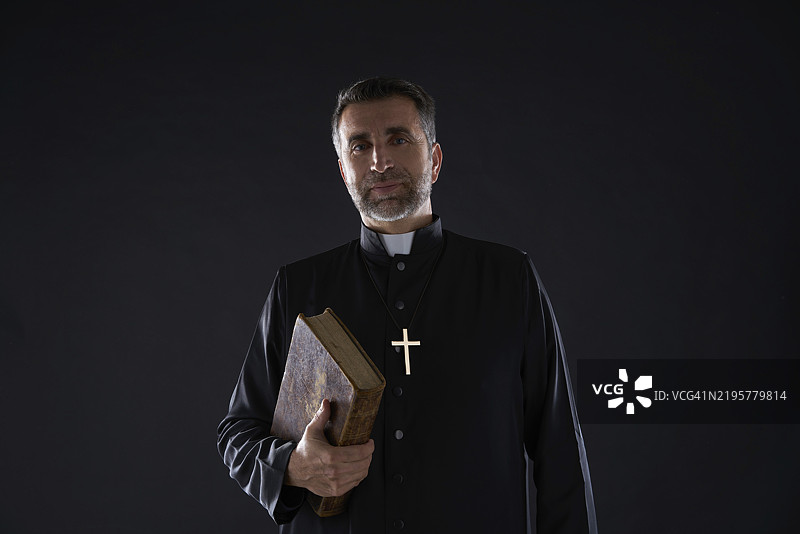 手持圣经的牧师肖像，背景纯色图片素材