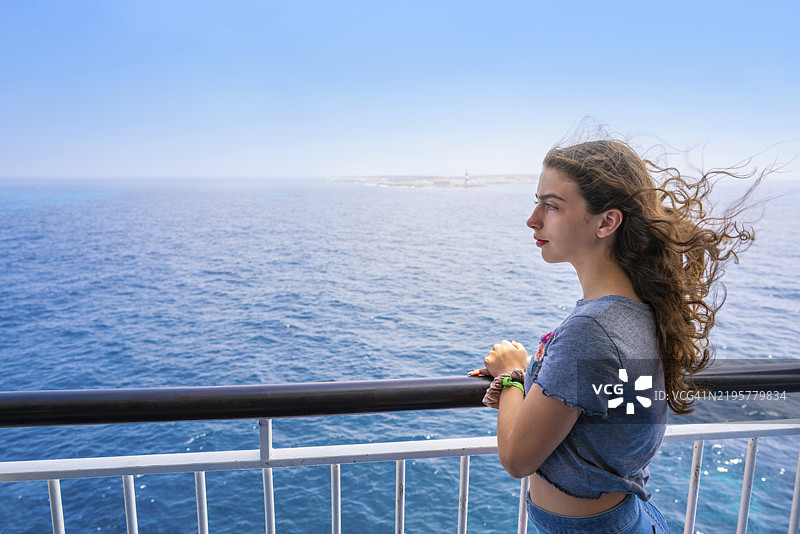 在西班牙伊比萨岛的福门特拉，女孩在船的栏杆上。图片素材