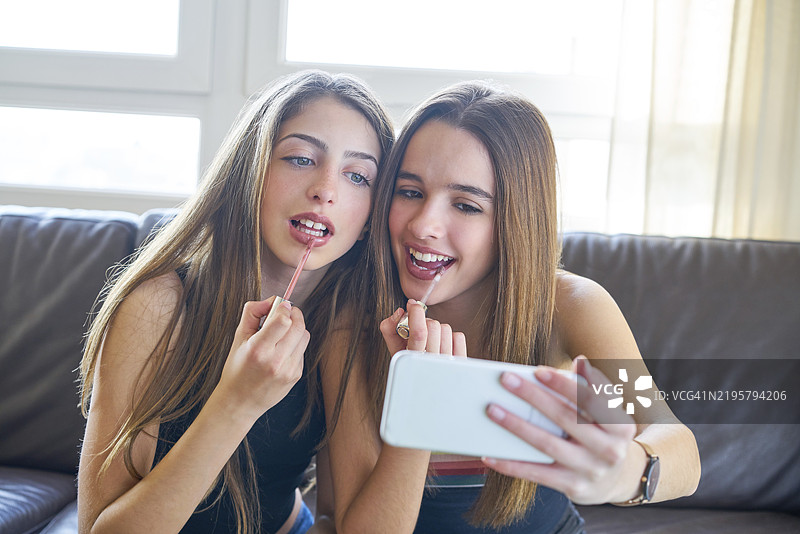 青少年女孩最好的朋友在智能手机上自拍化妆照图片素材