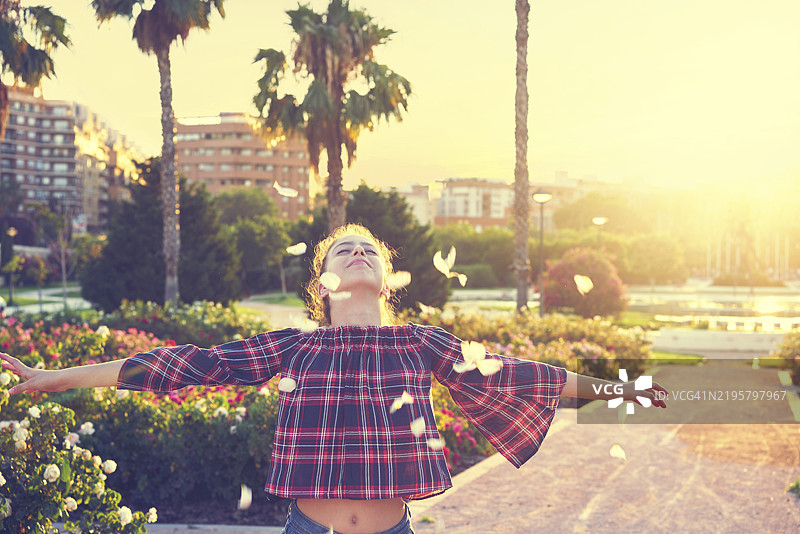 张开双臂的女孩在公园户外撒花瓣图片素材
