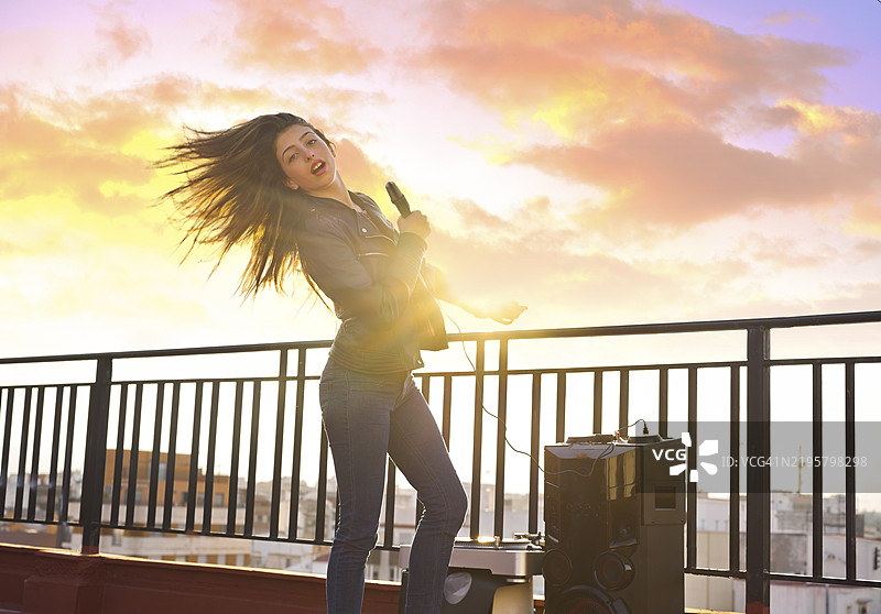 城市屋顶露台上的乐队女孩在户外唱卡拉OK图片素材