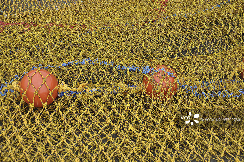 特写镜头：黄色渔网，配有红色浮标和蓝色绳索图片素材