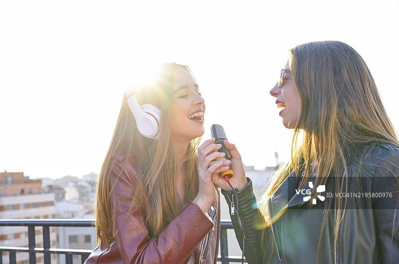 最好的朋友们在城市屋顶露台上唱卡拉OK的女孩乐队图片素材