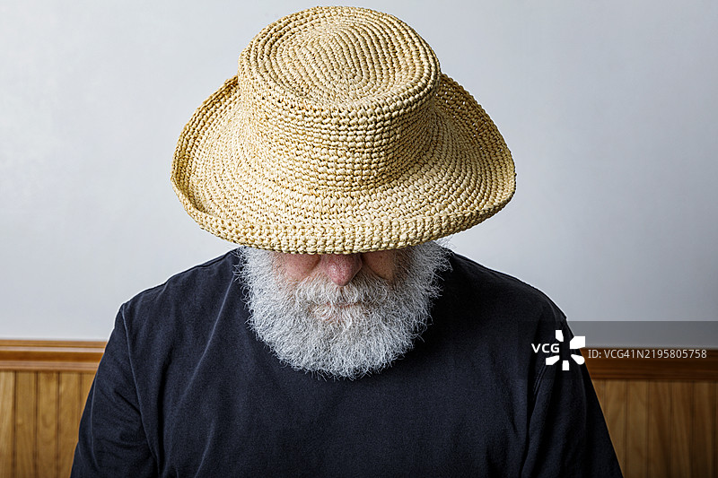 戴着草帽的灰胡子老人在低头看图片素材