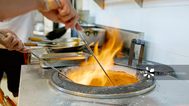 厨师在印度餐厅厨房中将串烧放入坦杜尔烤箱的特写镜头图片素材
