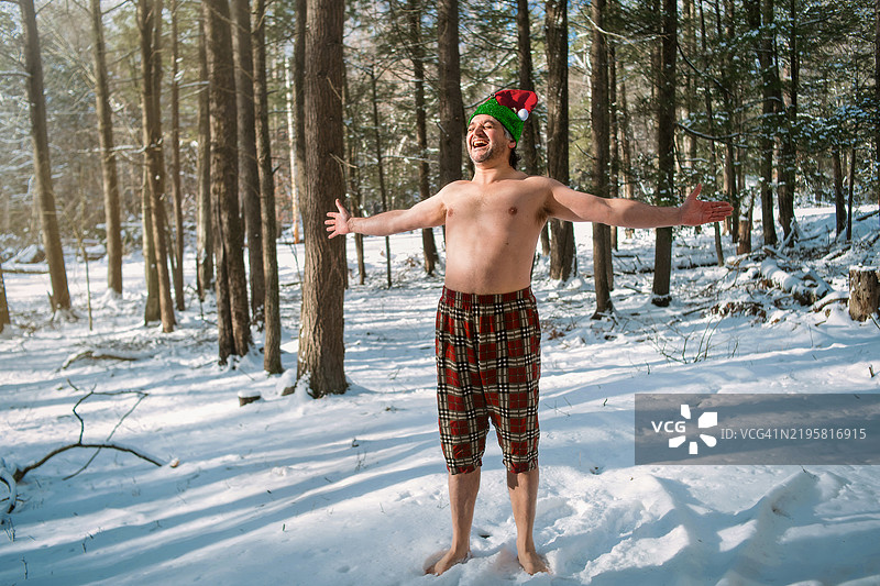 在自然中与大地连接。赤裸上身的成熟男性在宾夕法尼亚州的雪林中进行接地练习。图片素材