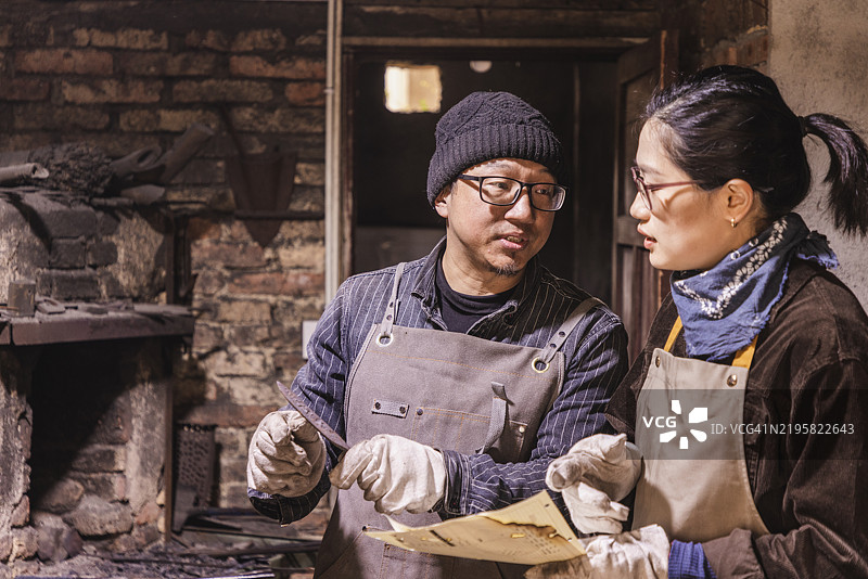 亚洲女性在铁匠工作坊学习锻造知识图片素材