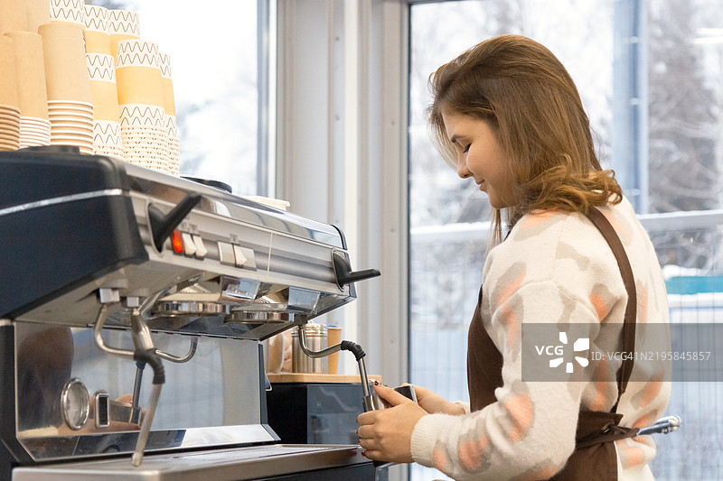 咖啡师在专业的意式咖啡机上制作咖啡饮品。冬季早晨的咖啡馆。图片素材