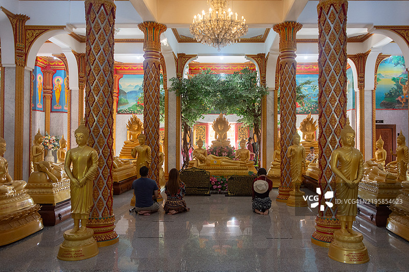信徒们在普吉岛的Wat Chaiyathararam寺内的Phra Maha Chedi祈祷佛像。图片素材