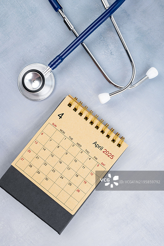 2025年4月桌面日历，手工棕色纸质日历与听诊器，医生预约概念。图片素材