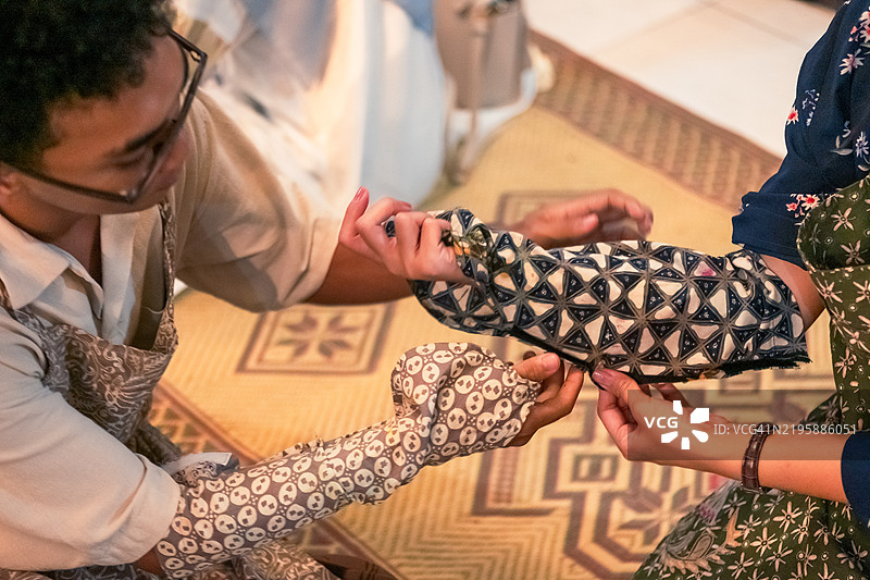 两个朋友用蜡染工作坊的袖子保护他们的手臂图片素材