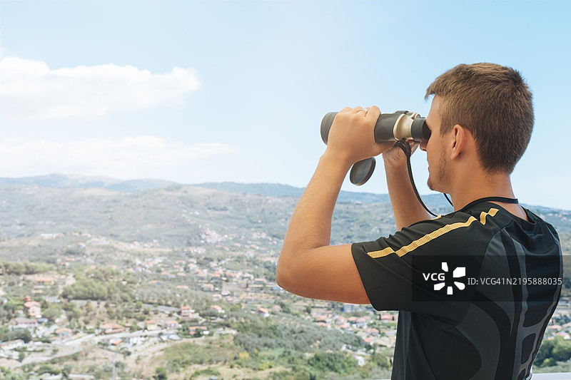 男子通过望远镜观察五彩斑斓的山脉全景图片素材