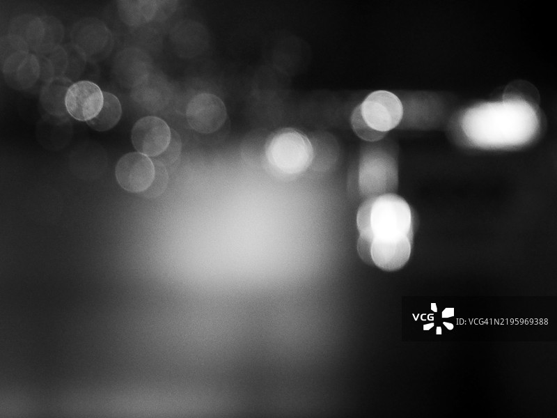 模糊的黑色背景上灰白色光点的照片。图片素材