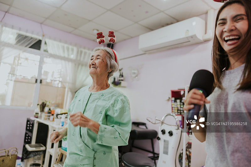 年长女性和家人在她的小美容院里享受舞蹈，庆祝圣诞节假期。图片素材