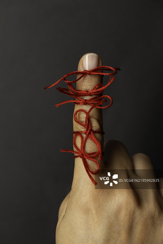 手指缠绕着红线，背景为深色图片素材