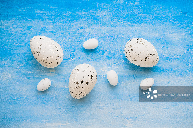 七个鹌鹑蛋躺在蓝白色的表面上。图片素材