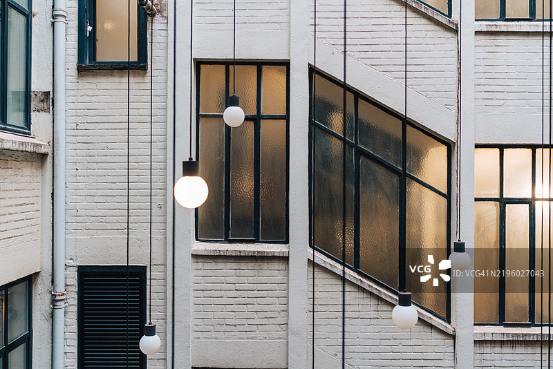 吊灯悬挂在白砖建筑的窗户上。图片素材