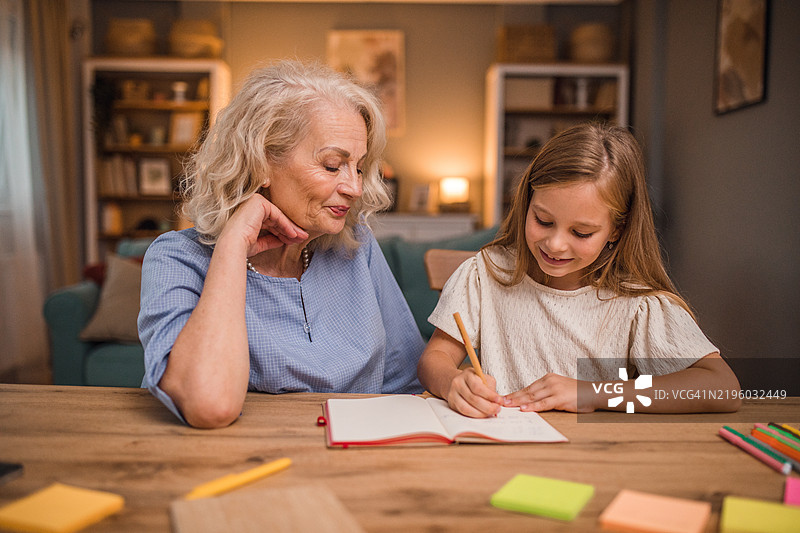 一个微笑的小女孩在祖母的帮助下学习图片素材