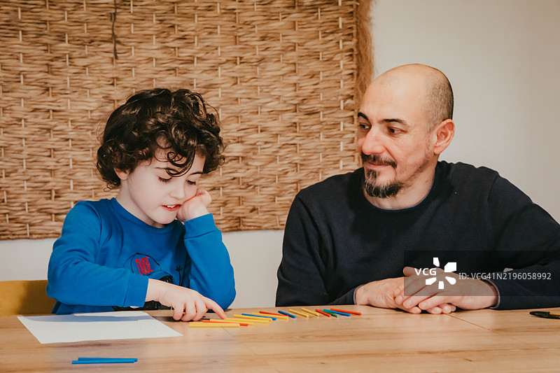 一个小男孩正在和他的爸爸学习数学图片素材