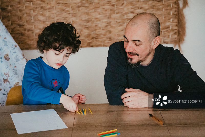 一个小男孩正在和他的爸爸学习数学图片素材
