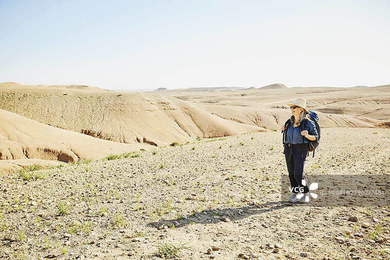 在阿加法伊沙漠中，背着背包的微笑老年女性远足的广角镜头图片素材