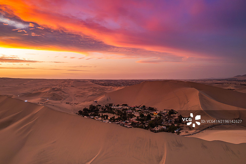 在华卡奇纳绿洲沙漠上空飞行的无人机，背景是五彩斑斓的日落天空图片素材